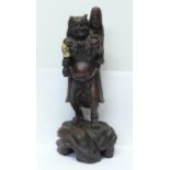 A carved Japanese figure of a demon carrying a woman on his shoulder, set with bone, inset signature