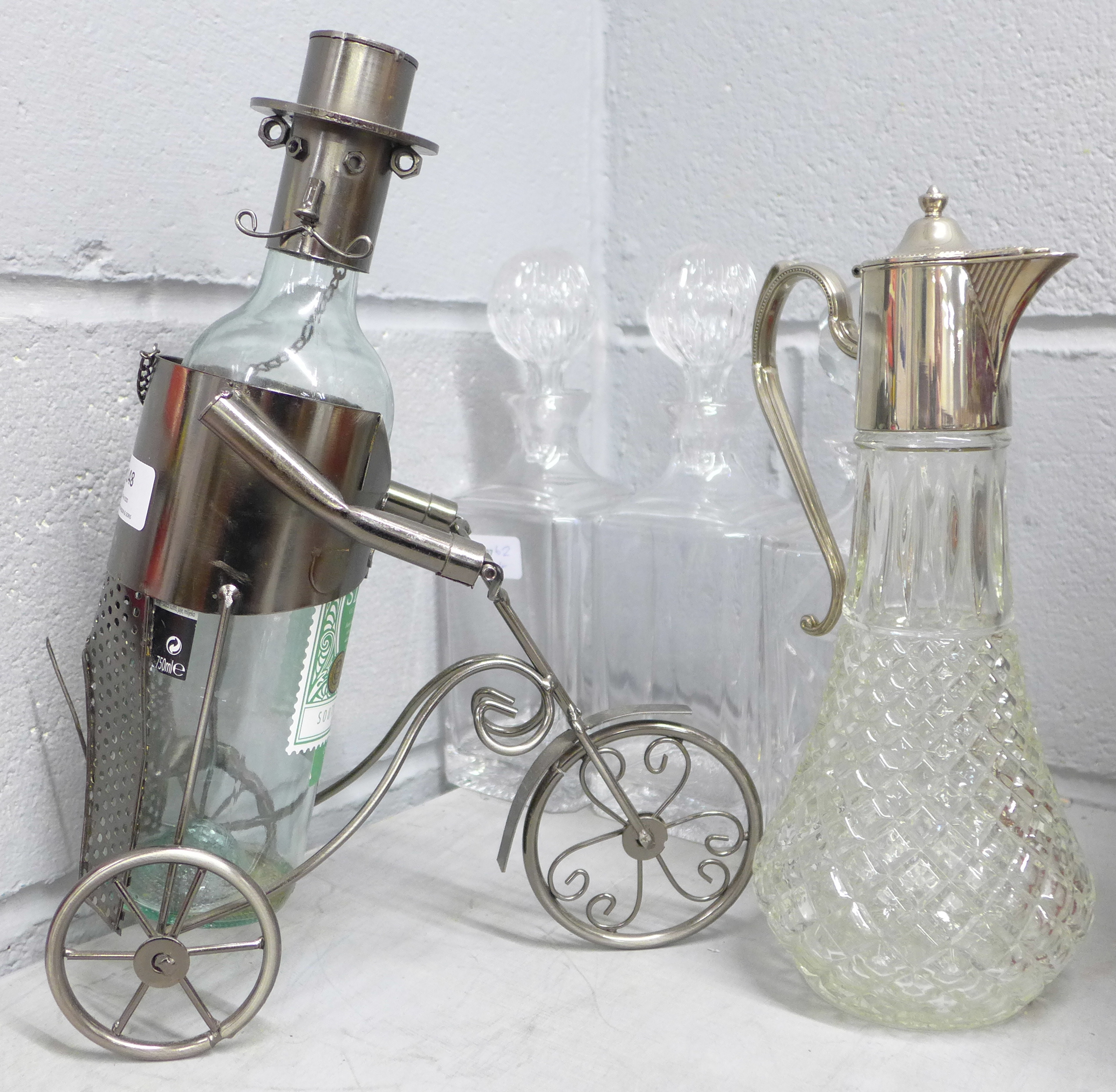 Three glass decanters, a claret jug and a novelty bottle holder