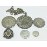 A George III silver half-crown, 1818, three other coins, a coin pendant and a silver badge