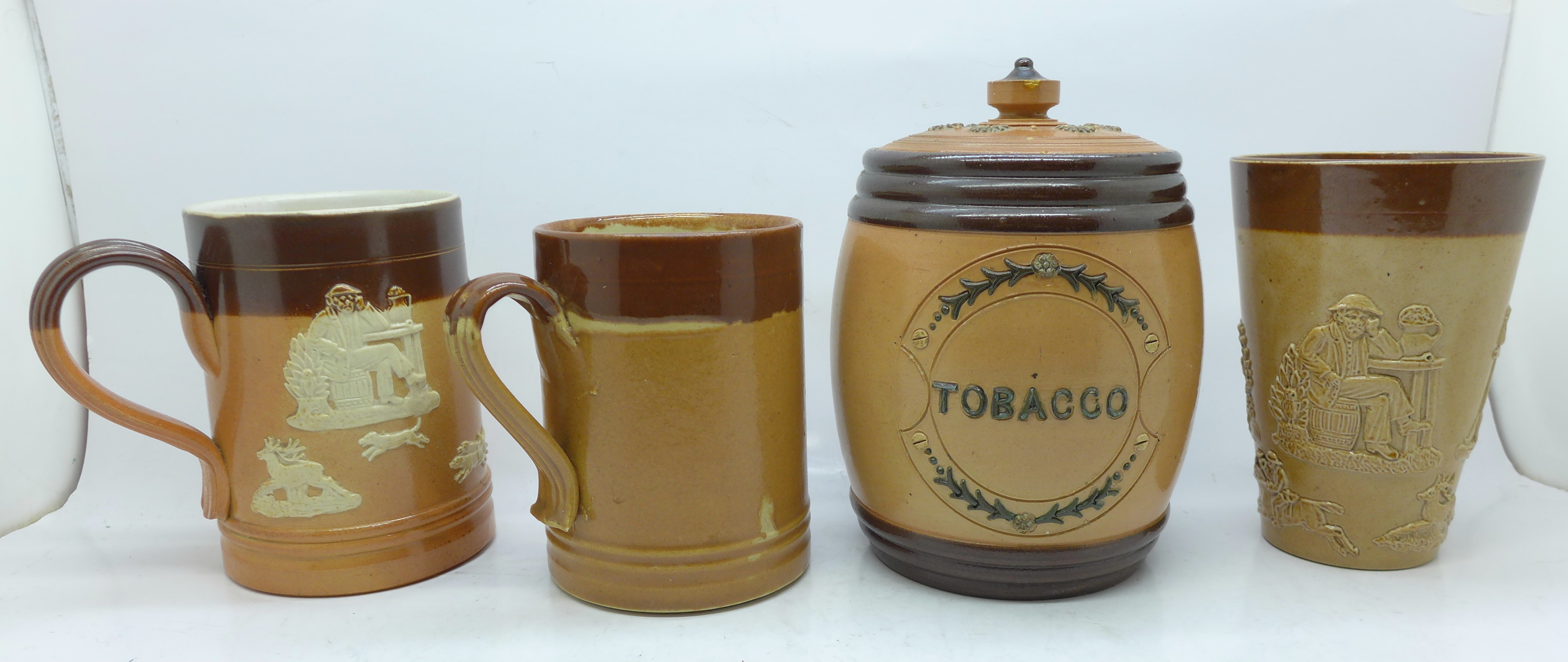 A Doulton Lambeth tobacco jar, two mugs and a beaker, chips on rim of tobacco jar