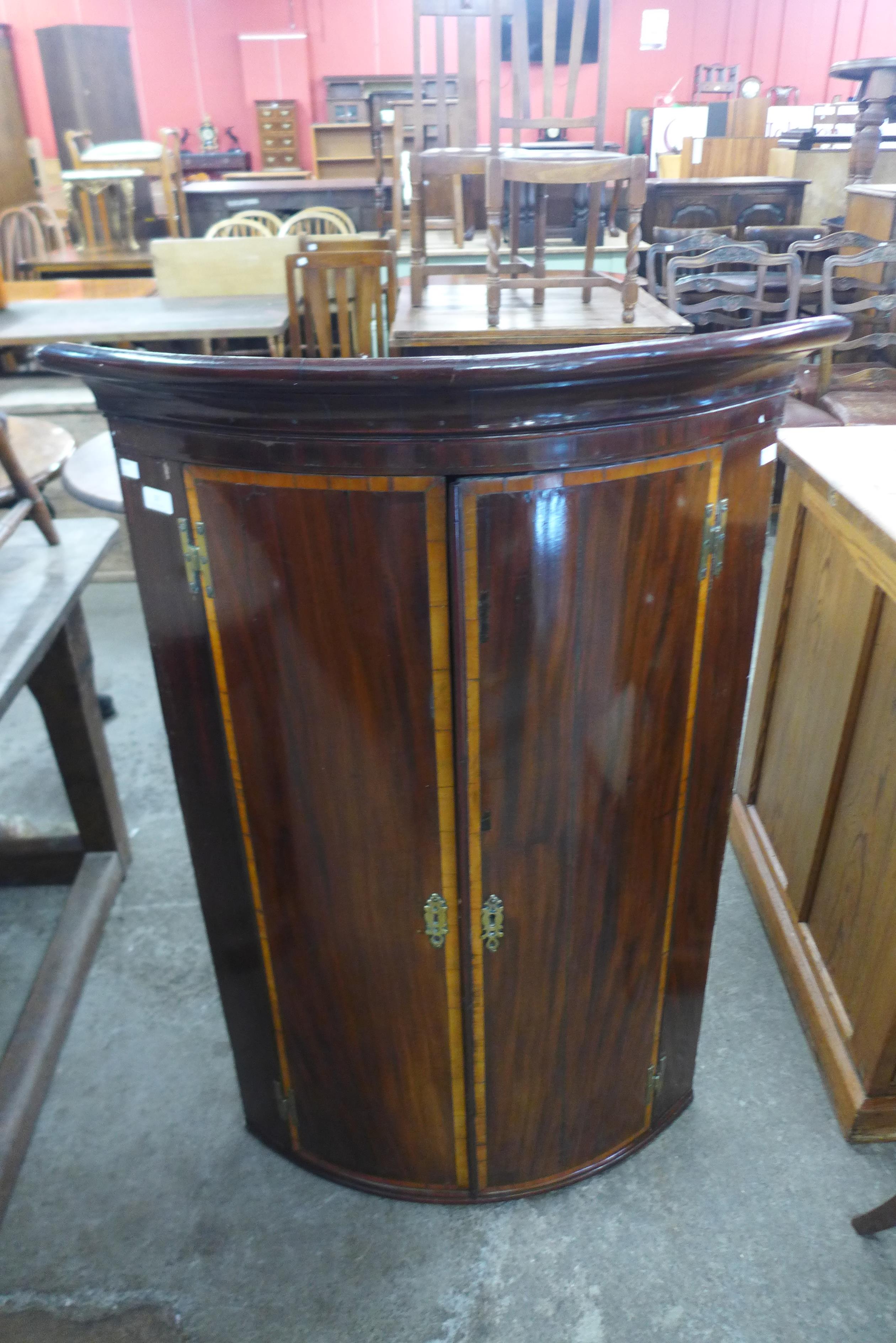 A George III inlaid mahogany bow front hanging corner cupboard