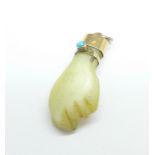 A carved ivory and yellow metal fist charm set with a turquoise