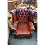 A red leather Chesterfield wingback armchair, a/f