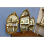 A pair of brass framed mirrors and one other similar