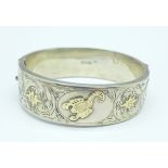 A silver bangle with gold applied decoration, 29g