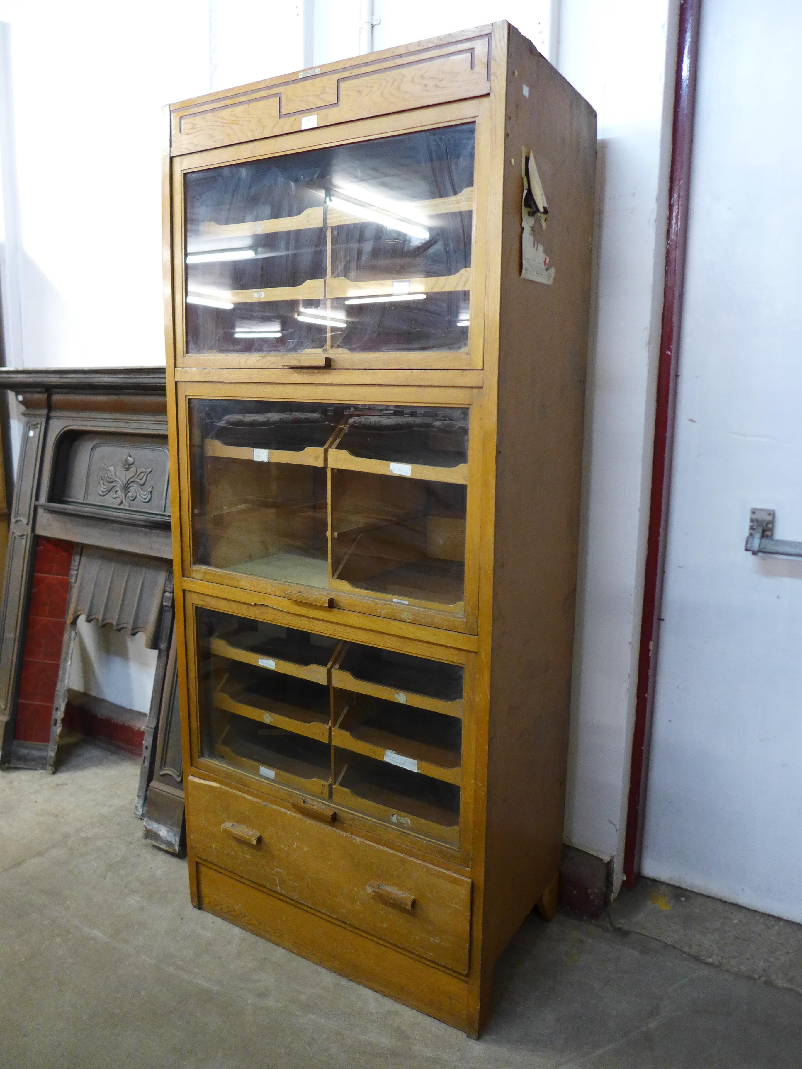 A mid 20th Century oak haberdashery shop cabinet