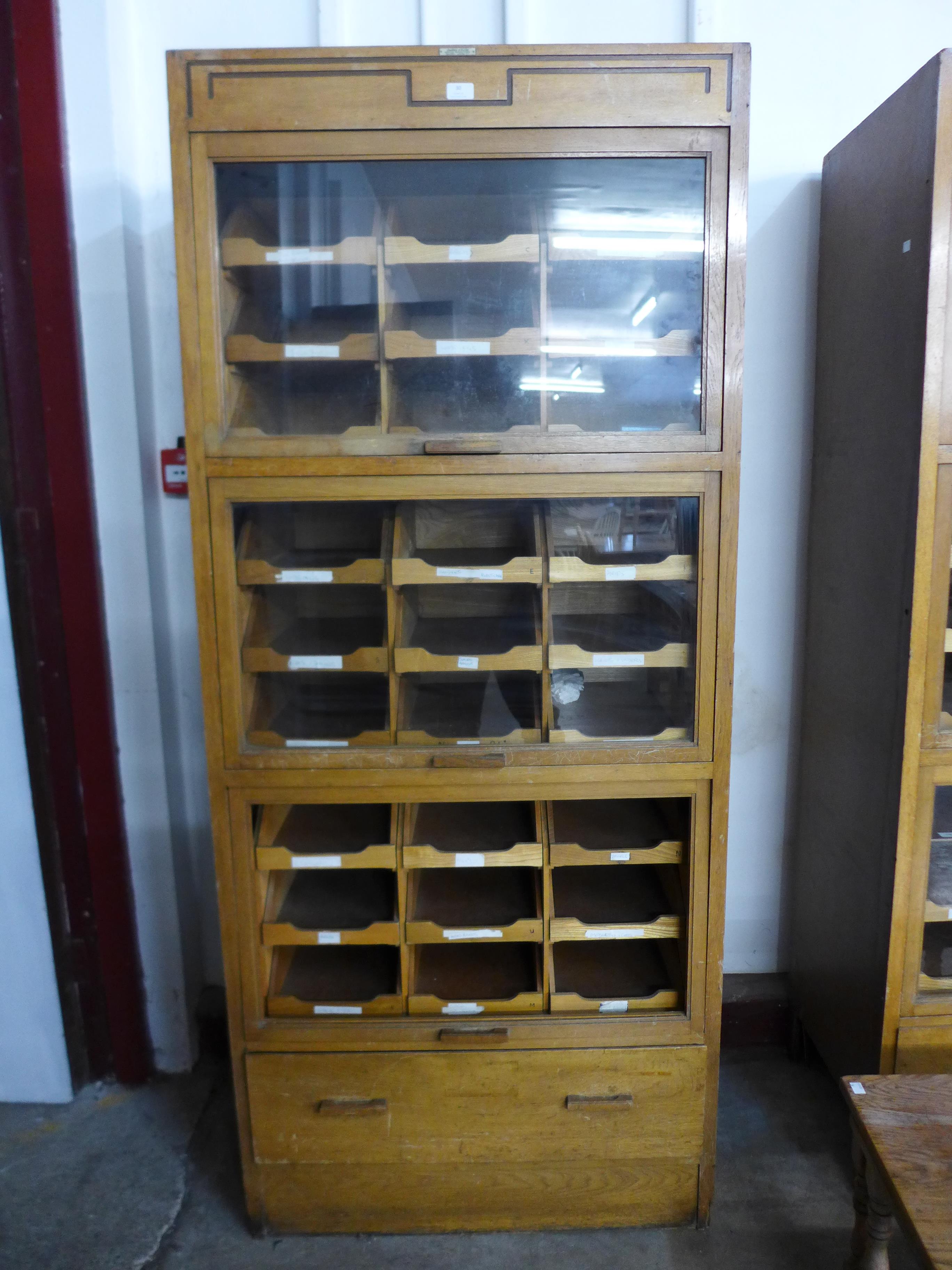 A mid 20th Century oak haberdashery shop cabinet