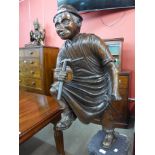 A carved wood figure of a blacksmith, on pedestal base