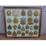 A framed set of 24 regimental cap badges plus a shoulder title