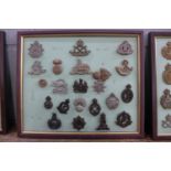 A framed set of 21 plastic regimental cap badges