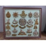 A framed set of 17 regimental cap badges plus shoulder titles