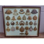 A framed set of 26 cap badges plus shoulder titles