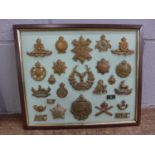 A framed set of 21 cap badges and others