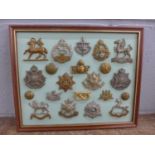 A framed set of 17 regimental cap badges plus buttons