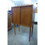 A small teak two door cabinet on stand