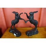 A pair of small bronze boxing hares, on green marble socles