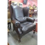A large mahogany and brown leather wingback armchair
