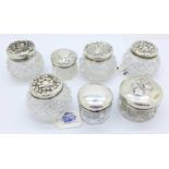 Seven small silver topped glass jars
