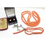 A twig coral pendant on a silver chain, a coral necklace, a large coral coloured bead necklace, a