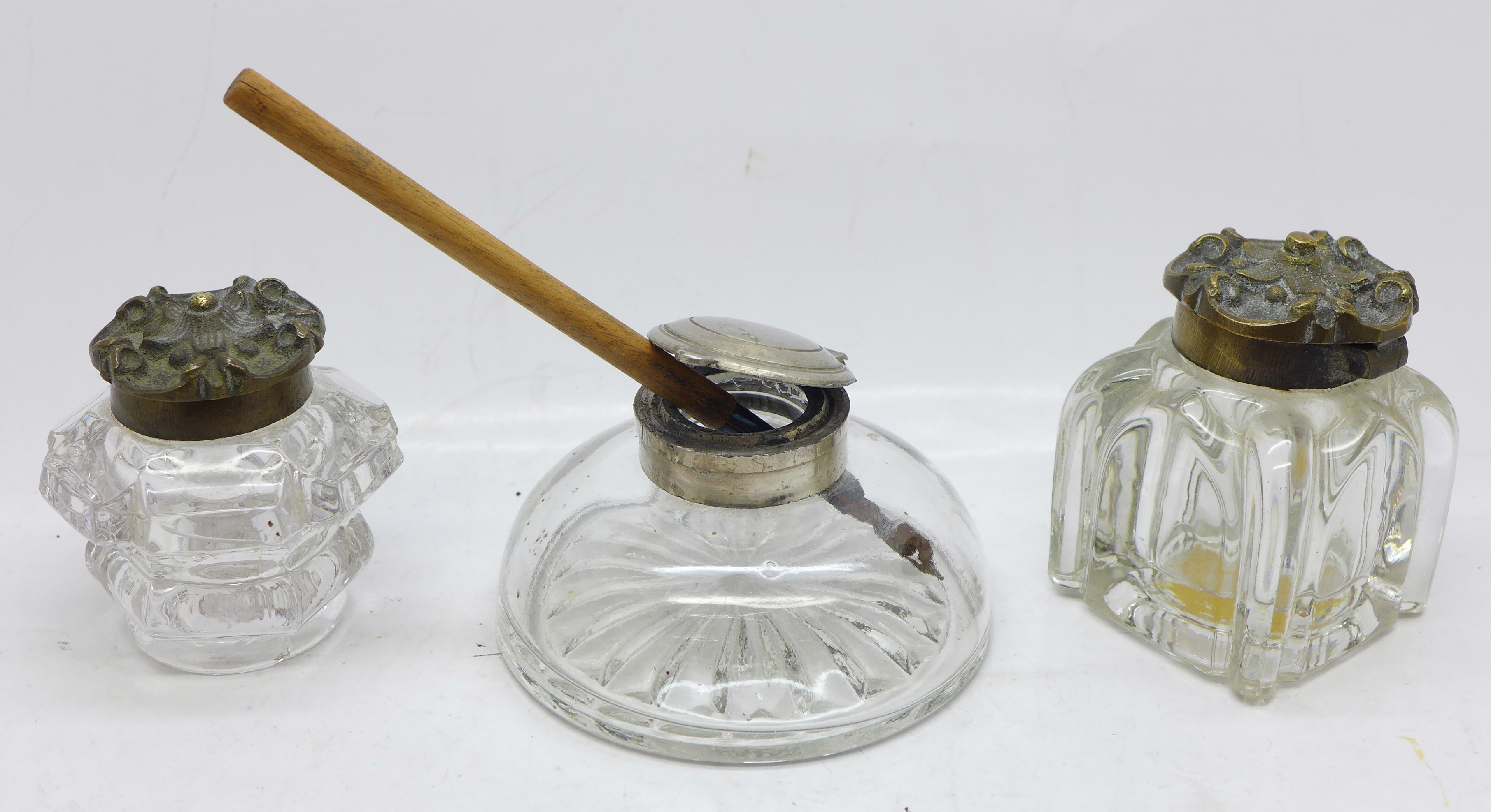 Three Edwardian glass inkwells and a dip pen