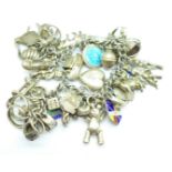 A silver charm bracelet with approximately forty charms including flags, Teddy bear, cupid, cow,