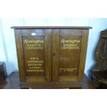 A mahogany two door cupboard, bearing painted Remington Sporting Cartridges inscription to doors,
