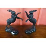 A pair of bronze boxing hares, on black marble socles, 30cms h