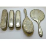 A silver backed hand mirror and four brushes