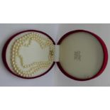 A three-strand pearl necklace with 9ct gold clasp set with garnets, cased
