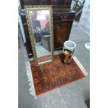 A small red rug, a gilt framed mirror and a stick stand