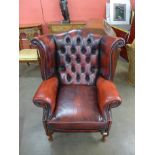 A beech and red leather Chesterfield wingback armchair
