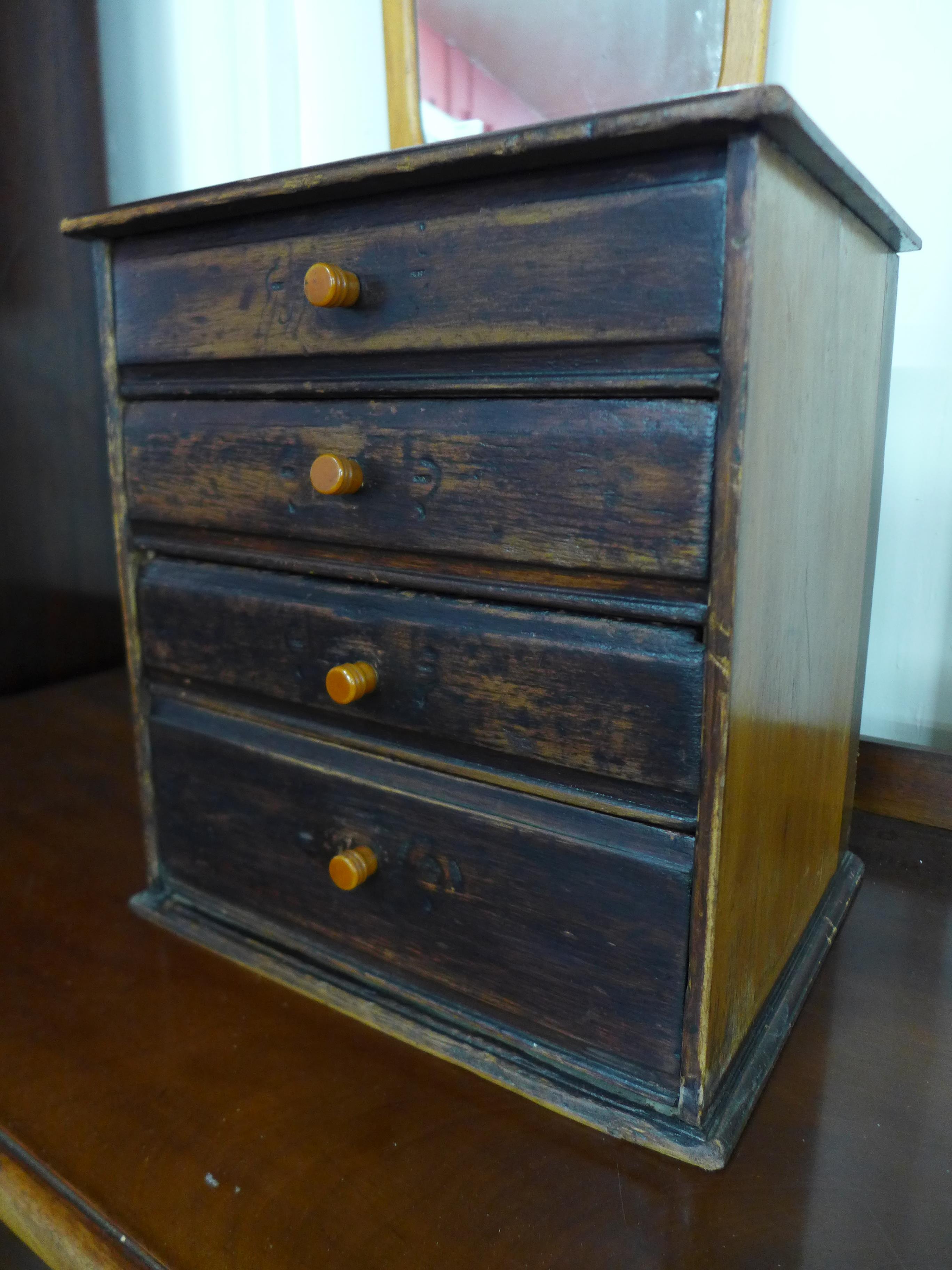 An early 20th Century canary wood table top four drawer chest, made by Henry Stone & Son, 36cms h,