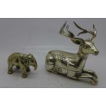 A white metal box in the form of a recumbant stag, stamped T90 and a model of an elephant, trunk a/f