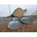 A set of three graduated frying pans and a pair of fire bellows