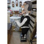 A painted wooden figural dumb waiter and a small Laurel & Hardy garden figure