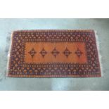 An eastern terracotta ground rug, 140 x 74cms