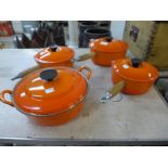 Four Le Creuset orange saucepans