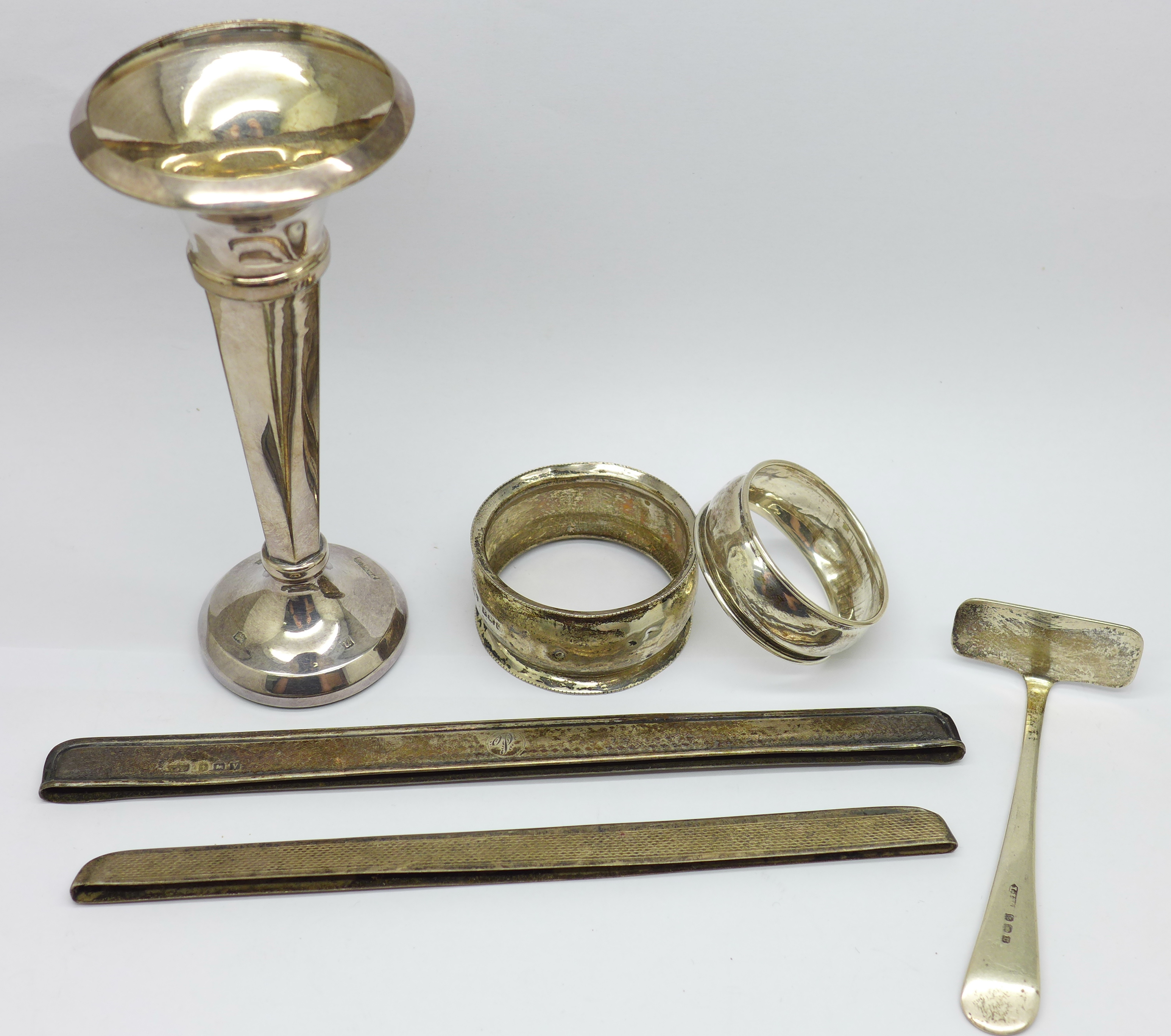 A silver posy vase, (weighted), two silver napkin rings, a silver pusher and two silver comb