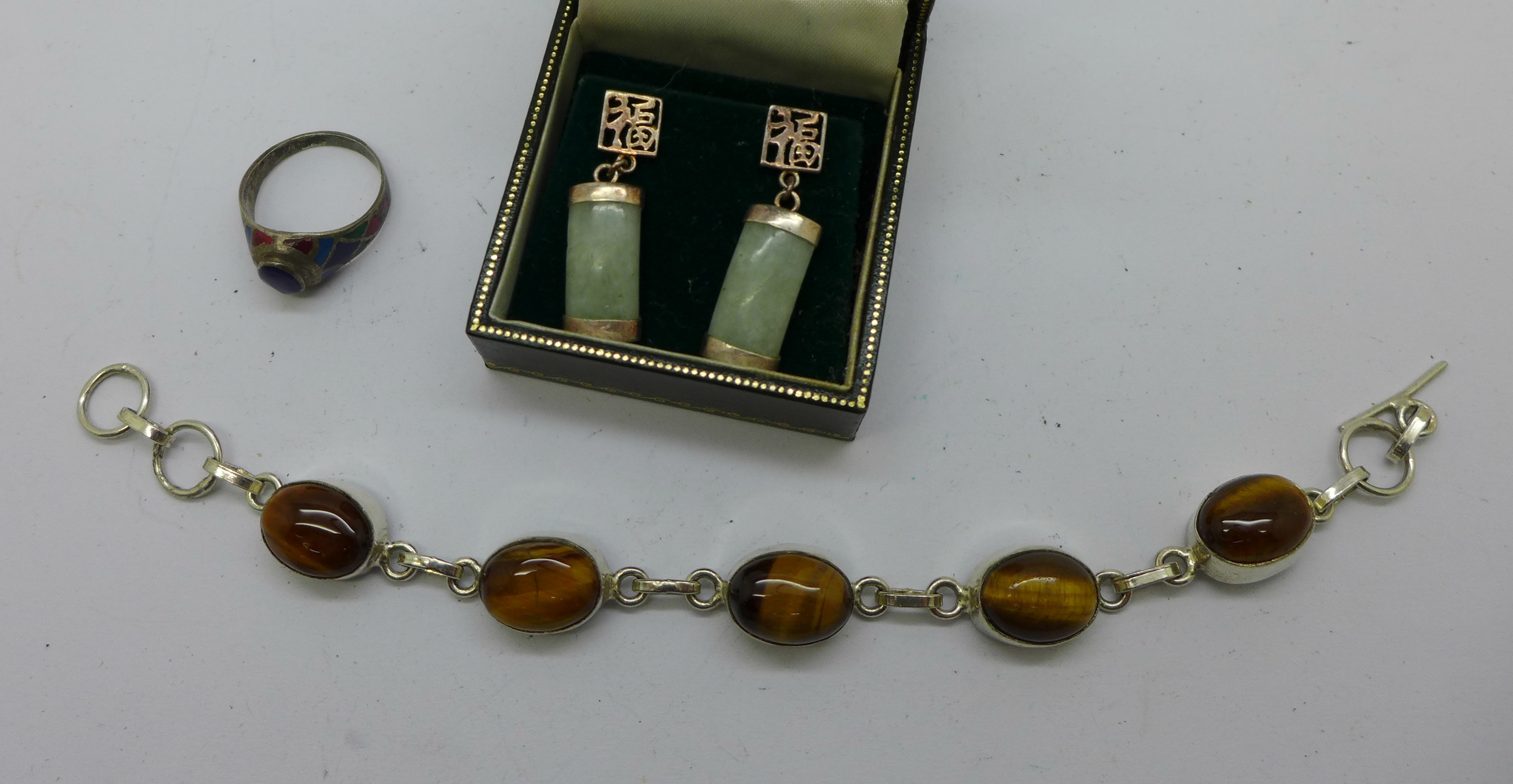 A silver and tigers eye bracelet, jade and silver earrings and a silver enamelled ring