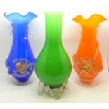 Three glass vases, bright orange, green and blue