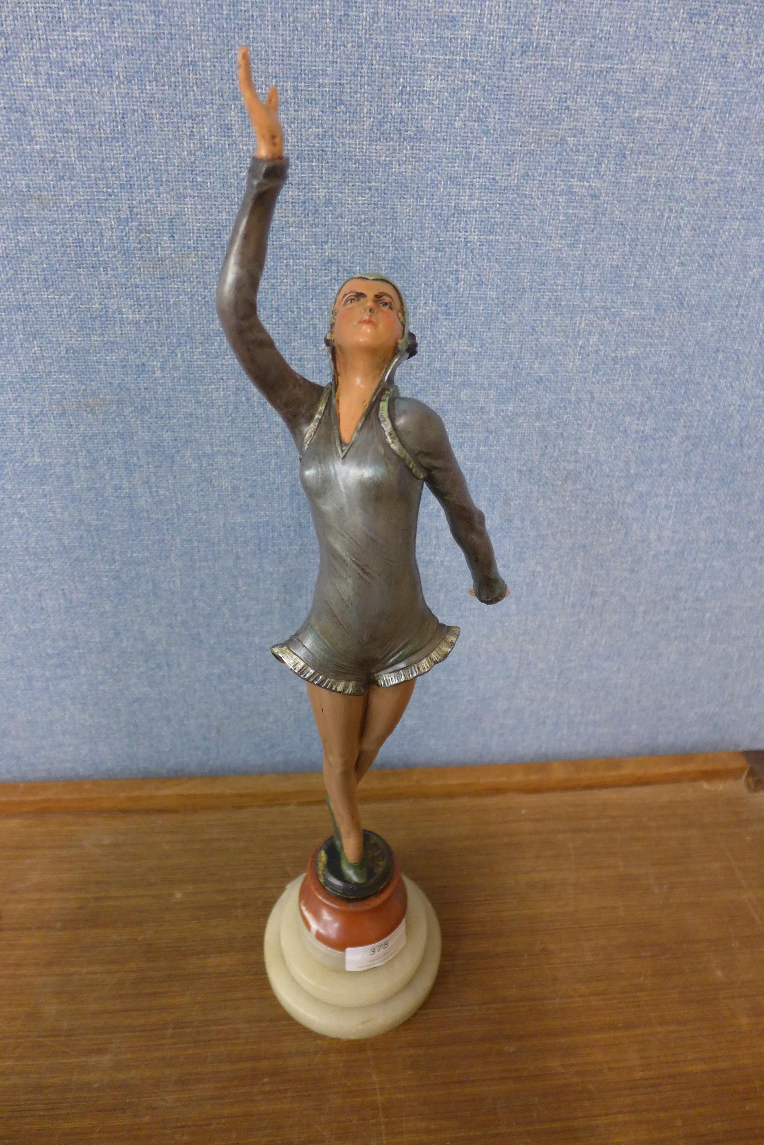 An Art Deco painted spelter figure of a lady, on onyx and marble socle