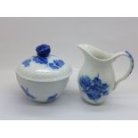 A Royal Copenhagen cream jug and sucrier decorated with blue flowers and with basket weave moulded