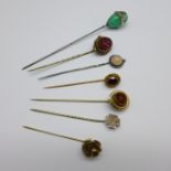 A collection of seven stick pins, including jade, garnet, etc.