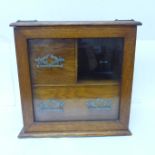 An oak smokers cabinet with bevelled glass door, with three pipe bowls, no tobacco jar