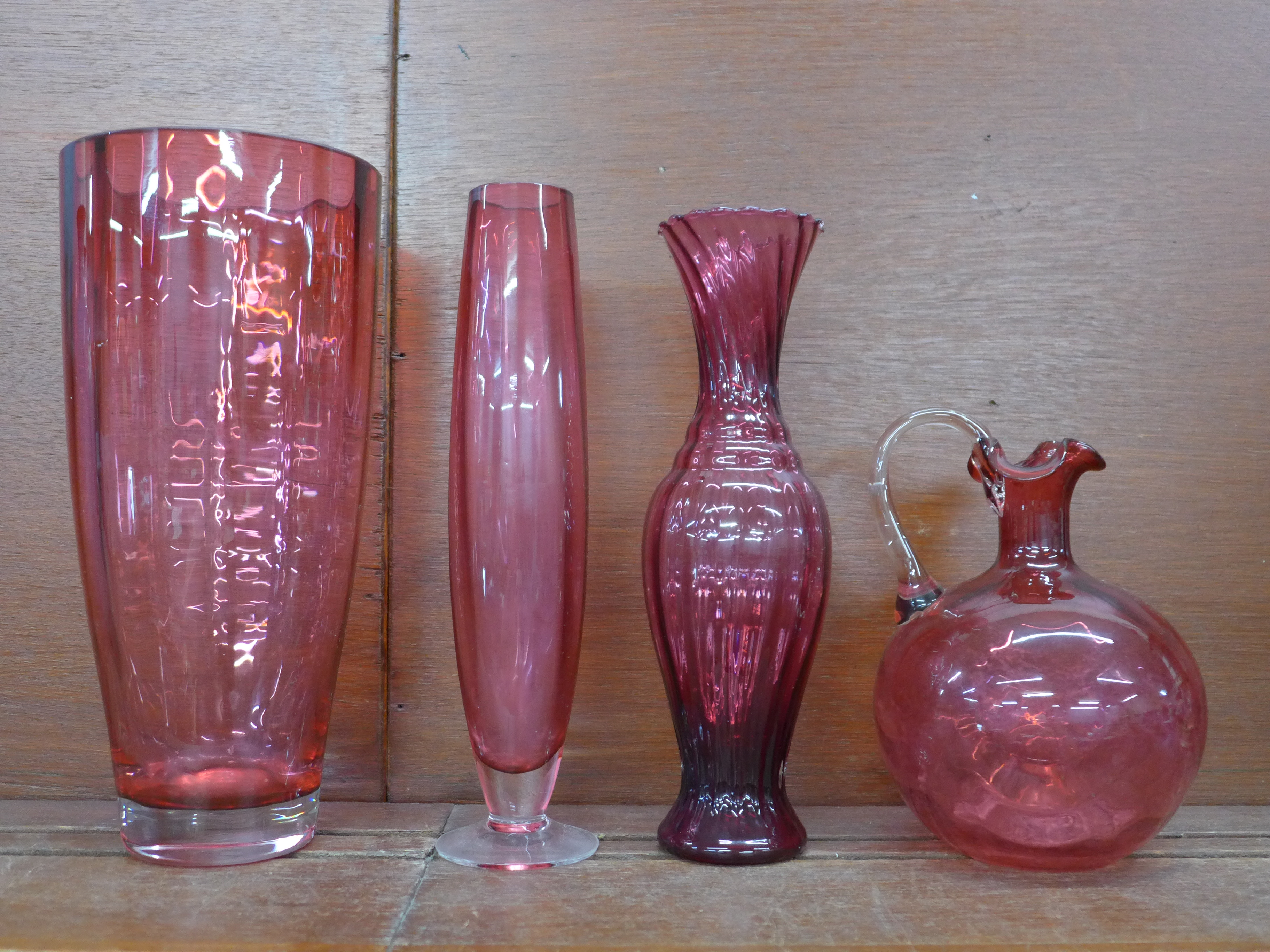 Four items of cranberry glass; large vase, 28cm, two other vases and a decanter, lacking stopper