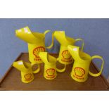 A set of five metal graduated Shell advertising jugs