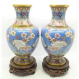 A pair of cloisonne vases decorated with storks, on wooden stands, 19cm