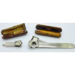 Two cigar cutters and two amber cheroot holders, cased, one with 9ct gold rim a/f
