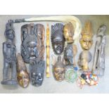 A collection of carved tourist pieces, wooden tribal masks, fly swat, etc.