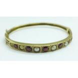 A 9ct gold, garnet and pearl bangle, 12.6g, one pearl missing, two pearls a/f, 12.3g